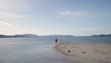 Young-caucasian-woman-in-red-beach-kaftan-walking-on-remote-sandbar-in-Asia-in-ultra-slow-motion