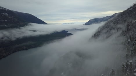 Wide-aerial-shot-of-a-valley-covered-by-winter-fog-in-Vancouver-Island,-Canada