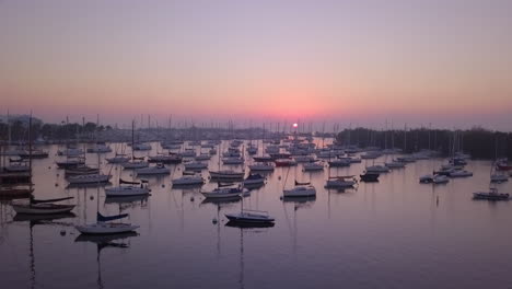 Aerial-fly-up-to-reveal-boat-filled-harbor-and-sunrise