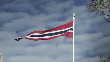 Bandera-Noruega-Ondeando-En-El-Viento-Con-Un-Cielo-Azul-Nublado-En-El-Fondo