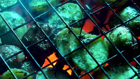 Closeup-of-herbed-new-potatoes-in-a-wire-basket-on-a-hot-grill-with-red-embers-glowing-beneath