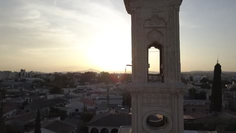 Aerial-shot-circling-a-church-tower-with-church-bells-ringing-at-sunset