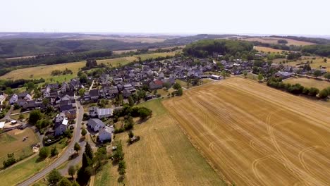 Flight-with-a-DJI-Phantom-4-Drone-around-a-rural,-german-village-located-in-rural,-agricultural-area