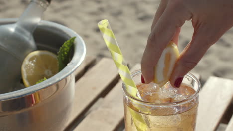 Close-up-of-a-lemon-being-squeezed-into-drink-with-straw-in-slow-motion,-sunny-day,-Slowmo