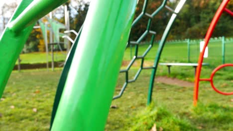 Slow-revealing-shot-through-children's-play-area-climbing-frame-metal-coloured-bars