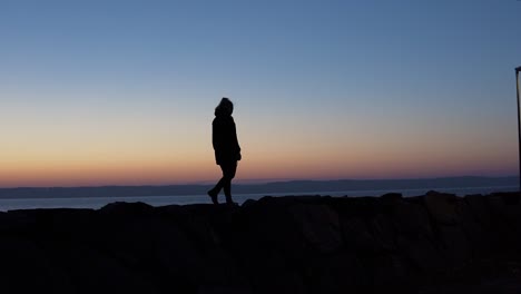A-silhoutte-of-a-girl-walking-on-rocks-during-blue-hour