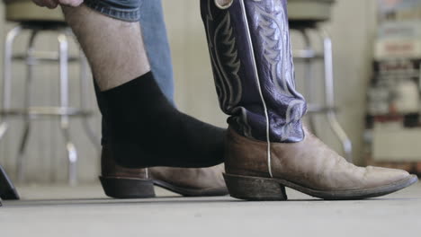 Sitzender-Mann,-Der-Cowboystiefel-Anzieht-Und-Jeans-In-Zeitlupe-überzieht