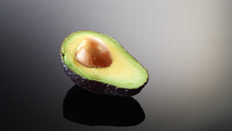 A-ripe-green-avocado-cut-in-half-with-the-pit-isolated-on-a-black-and-white-background