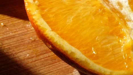 Makroaufnahme-Einer-Reifen-Orangenfruchtscheibe-Mit-Saft,-Der-Im-Sonnenlicht-Auf-Einem-Schneidebrett-Für-Einen-Gesunden-Snack-Abtropft