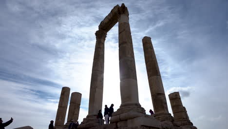 Turistas-Tomando-Fotos-Debajo-Del-Alto-Templo-De-Mármol-Blanco-De-Las-Columnas-De-Hércules-En-La-Colina-De-La-Ciudadela-En-Un-Día-Soleado-En-Amman