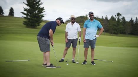 Three-friends-putting-on-a-golf-course-in-slow-motion