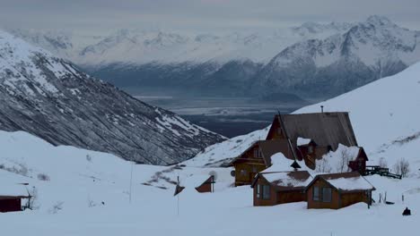 Aerial-pan,-Beautiful-Alaskan-wilderness-at-Hatcher-Pass,-lodge-covered-in-snow-with-mountains-in-distance