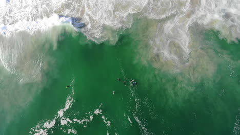 overview-Drone-footage-of-bodyboarders-and-surfers-in-water,-sea-with-waves-rolling-in