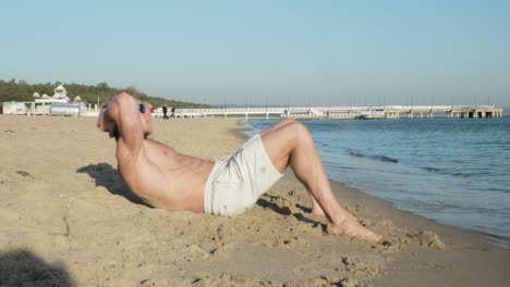 An-athletic-man-does-crunches-on-the-beach