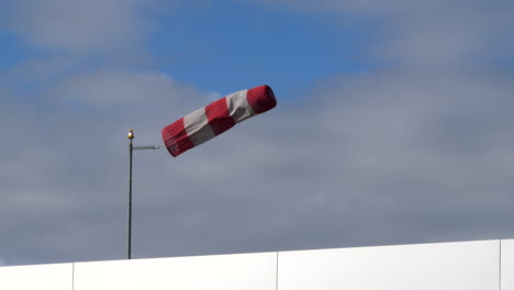 An-isolated-windsock-at-an-airfield-in-heavy-winds-to-a-backdrop-of-white-clouds-and-blue-sky-CROPPED