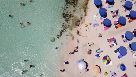 Aerial-overhead-footage-of-people-bathing-at-a-shallow-sandy-beach