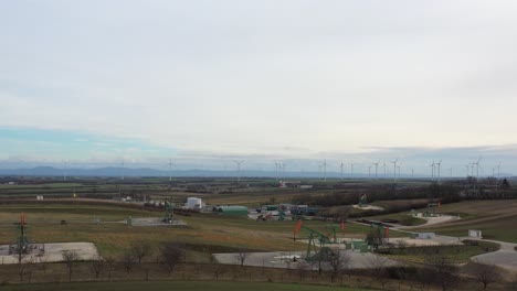 [DRONE]revealing-shot-of-a-scenery-with-multiple-oil-derricks-moving-and-wind-turbines-in-the-background