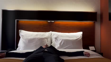 Tired-male-business-traveler-falling-into-hotel-room-bed