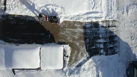 Aerial-top-view-of-man-using-snow-blower-on-driveway