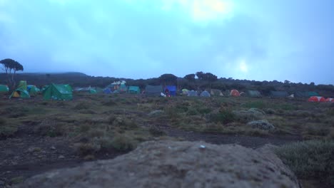 Toma-Estática-Del-Campamento-De-Caminata-Kilimajaro-Con-Carpas-Y-Gente-Caminando