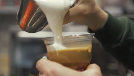 Pouring-frothy-cream-over-freddo-cappuccino-in-slow-motion