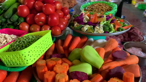 Große-Auswahl-An-Frischem-Gemüse-Wie-Karotten,-Chayote,-Tomaten-Und-Vielem-Mehr-Zum-Verkauf-Mit-Einer-Damenhand-Im-Hintergrund