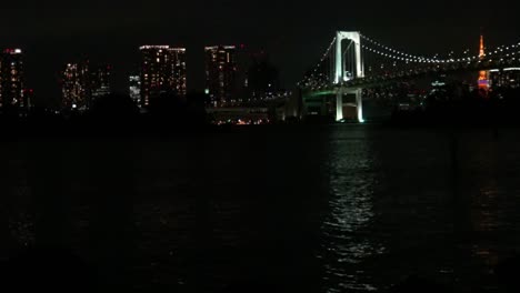 Timelapse,-Modern-business-district-with-skyscrapers-and-Rainbow-Bridge-at-night-in-Tokyo