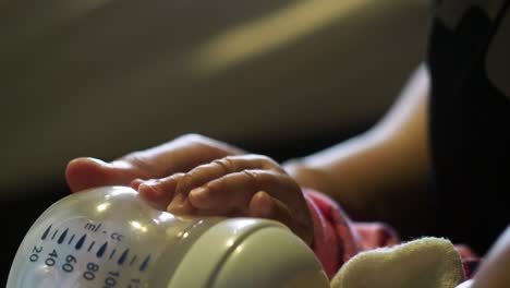 Closeup-of-asian-Baby-girl-holding-milk-bottle-while-feeding