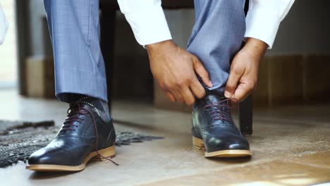Groom-putting-on-shoes-at-his-wedding