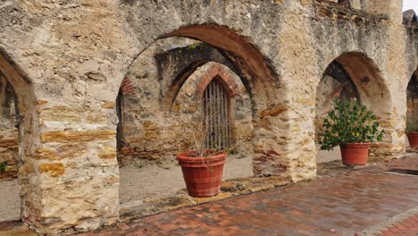 walking-through-old-mission-arches,-plant-pots-and-colorful-brick-work,-stone-and-tiled-floor