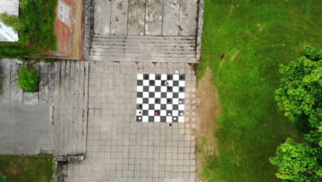 AERIAL:-Medium-Shot-of-Drone-Lift-Up-Above-Children-Playing-Chess-Game-Which-is-Painted-on-the-Bricks-on-the-Ground