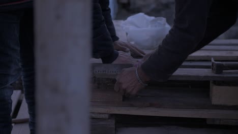 Afghan-refugees-cutting-pallet-wood-for-shelter