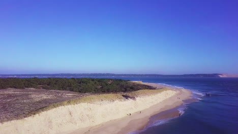 Aerial-shot-pan-right-pedestal-up-from-Cap-Ferret-through-sea-to-Pyla-dune,-South-France