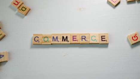 A-table-with-scattered-wooden-letters-and-a-person-spelling-Commerce