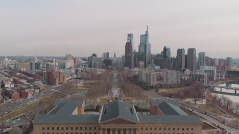 Aerial-over-Art-Museum-in-Philadelphia-facing-downtown-skyline-with-traffic-driving-on-roads