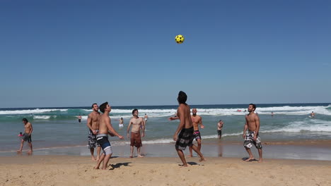Eine-Gruppe-Von-Freunden,-Die-Es-Genießen,-Im-Hochsommer-Am-Strand-Fußball-Zu-Spielen