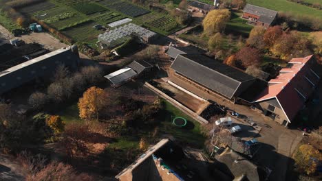 Luftaufnahme-Von-Hinter-Einem-Biologisch-Dynamischen-Bauernhof-In-Den-Niederlanden-Mit-Einer-Vielzahl-Von-Gebäuden,-Scheunen,-Gewächshäusern,-Kulturen-Und-Weideland