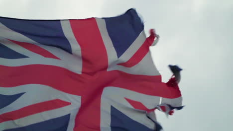 Close-up-old-torn-Union-Jack-flag-in-strong-winds-in-slow-motion