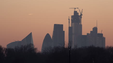 --Birds-fly-past-and-a-man-walks-in-front-of-the-City-of-London-skyline-at-sunset
