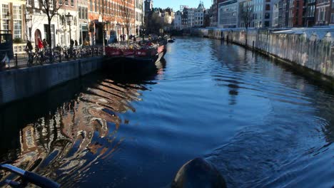 Boat-going-through-one-of-the-main-Amsterdam-canals-and-pretty-buildings-around