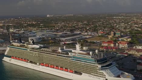Aerial-view-of-the-cruise-ship-in-dock-with-the-island-in-the-background-and-tilting-the-camera-up-into-the-skies