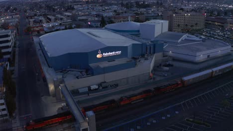 Aerial-drone-view,-train-slowly-passing-Rabobank-Arena,-Bakersfield,-California