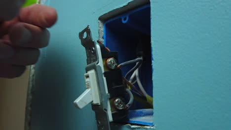 Pulling-a-switch-out-of-a-wall-box-and-unscrewing-and-removing-two-wires