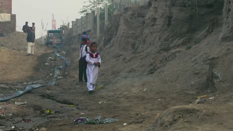 Pakistanische-Ländliche-Schulkinder-Auf-Der-Straße-In-Weißer-Uniform,-Ein-Abwasserrohr,-Das-Von-Der-Untergebauten-Hügeligen-Straße-Ausgeht