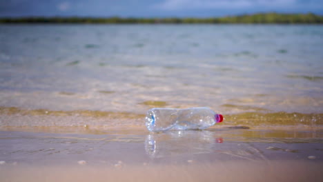 Plastikflasche,-Die-Von-Außerhalb-Des-Rahmens-In-Kleine-Wellen-Geworfen-Wird,-Die-Am-Sandstrand-Umspülen