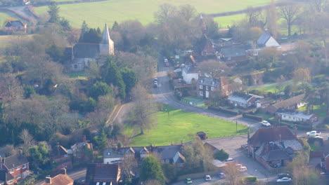 Weite-Luftaufnahme-Des-Dorfes-High-Halden-In-Kent,-Großbritannien,-Mit-Einem-Schwenk-Nach-Oben,-Der-Den-Dunst-Der-Wintersonne-über-Der-Landschaft-Offenbart