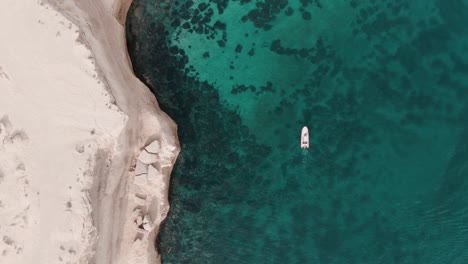 Boat-moving-next-to-a-cliff-in-patagonia-from-a-drone-top-shot-sixty-fps