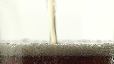 Macro-closeup-pouring-and-rising-of-cola-or-caramel-fizzy-drink-in-a-glass