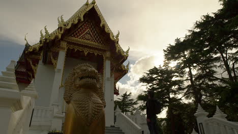 Tourist-man-arriving-at-a-Thai-Buddhist-Temple-at-sunset-time-and-looking-in-the-distance