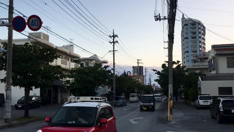 Cars-Driving-Down-Suburban-Street-in-Okinawa,-Japan-At-Dusk